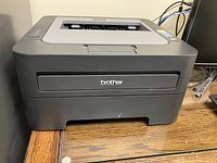 Front angled view of the black Brother HL-2240 laser printer showing the Brother logo and paper output slot.