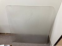 Clear floor protector mat with visible signs of wear, placed against a white background.