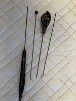 Four vintage hat pins laid on quilted fabric background, showing decorative handles and pins of different designs.