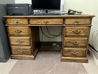 Front view of Kaufman oak executive desk with three top drawers and six lower drawers, dark wood finish.