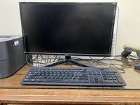 Full view of the monitor setup showing the Onn brand monitor, wired keyboard and wired mouse on a wooden surface.