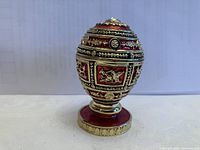 Front view of the ornate decorative globe trinket box showing detailed relief and colored accents.