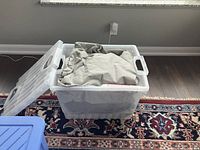 Two plastic storage bins containing the beige fabric outdoor furniture covers.