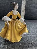 Full side view of Stephanie figurine showing posture and yellow dress.
