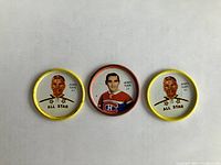 Three hockey coins featuring Jacques Plante, two All Star yellow rim coins and one Montreal Canadiens jersey coin with orange rim.