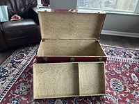 Open trunk showing inside wood grain patterned lining and removable storage shelf placed in front.