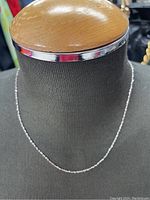 Full view of the gold necklace displayed on a mannequin bust showing the length and chain style