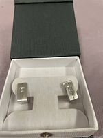 Pair of rectangular 925 sterling silver earrings with a cubic zirconia stone in each, presented in white cushioned box with black lid.