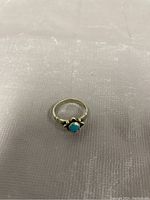 Close-up of the sterling silver ring with turquoise stone on a cloth background showing the band and stone.