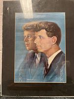 Front view of framed lithograph showing JFK and RFK portraits in formal attire with signature and text.