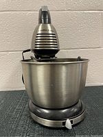 Front view of Hamilton Beach stand mixer with stainless steel bowl, showing ventilation slats, power switch and knob on base.