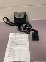 Full kit arranged including Kodak EasyShare camera, coil strap, lens cap, battery charger, camera case, and instruction manual laid on a flat surface.