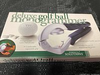 Front view of boxed deluxe golf ball monogrammer tool showing product image, brand Perfect Solutions, and features.