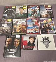 Nine DVDs and two CDs arranged on a gray surface, all new in packaging with visible front cover images.