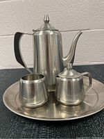 Front view of the full four-piece vintage Oneida stainless steel coffee serving set on the round tray.