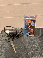 Photo of the Paw Patrol lightshow projector with stake and power cord placed on floor.