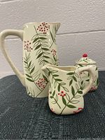 Set of ceramic serving items including pitcher, creamer, and sugar dish, showing the overall design and arrangement.