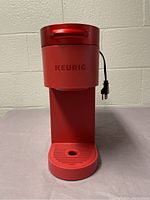 Front view of the scarlet red Keurig K-Slim coffee maker showing brand logo and front tray.