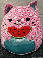 Front view of pink spotted leopard Squishmallow holding watermelon with smile and embroidered details
