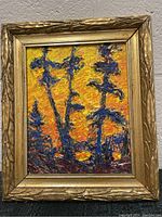 Framed textured painting showing silhouetted trees against a yellow and orange sunset background, with thick paint strokes creating texture.