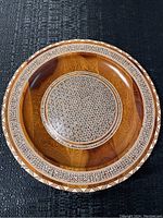 Top view of wooden plate showing circular shape and fine mosaic inlay pattern across center and surrounding rim