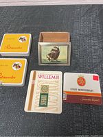 Lot of five vintage tins including two Pikeur Ritmeester, one Willem II, one Henri Wintermans, and one wooden box with ship image