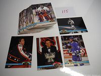 Stack of hockey cards with some cards laid out showing players in action and posed shots, including visible number 115 from the lot count.