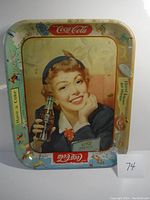 Full view of metal serving tray showing woman holding a Coke bottle, with Coca-Cola logos and decorative holly borders.