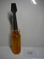 Vintage amber glass bottle filled with liquid, shaped like a screwdriver with a silver-colored flathead cap.