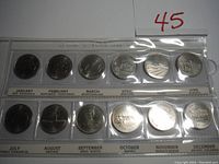 Full view of the coin set in plastic holder showing all 12 provincial/territorial coins arranged by month from January to December with labels.