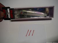 Full view of the unopened Rapala Husky Jerk lure in retail packaging, showing lure and hooks inside clear plastic box