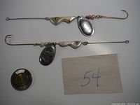 Two vintage fishing lures laying side by side showing full length including hooks, beads, wavy metal sections, and spinner blades.