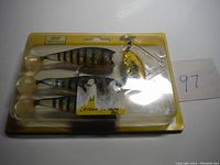 Photo showing three Wildeye Spin Shads fishing lures in original packaging, featuring paddle tails and treble hooks with a gold spinner blade attached to one lure.