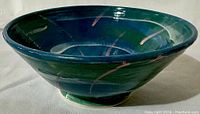Side view of the blue-green wheel thrown ceramic bowl showing the shape and glaze details with pink streaks.