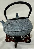 Cast iron teapot on the wooden stand showing side profile and handle