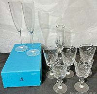 Complete stemware set with six cut crystal glasses including five wine glasses and one champagne flute, plus Birks boxed champagne flutes on left.