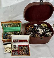Overview of four jewellery boxes filled with assorted costume jewellery including bracelets, necklaces, brooches, earrings, and cufflinks