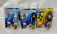 Three Mego 8 inch action figures in original packaging: Marcia Brady from The Brady Bunch, Prue Halliwell from Charmed, Gene Simmons The Demon from KISS.