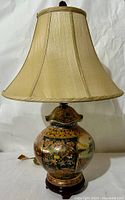 Full view of the Satsuma porcelain lamp with sheer beige shade, showing intricate hand-painted base and flared silk-like shade