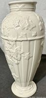 Front view showing full profile of ivory white fluted vase with raised ivy design.
