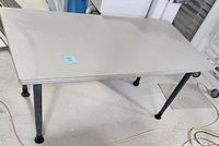 Full view of utility table showing solid wood surface and black metal legs on a workshop floor.