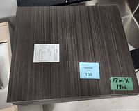 Stack of wooden sheets showing the top sheet's wood grain pattern and finishes, with measurement label visible.