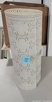 Rolled white carpet runner with beige geometric pattern, standing upright in front of a cardboard box.