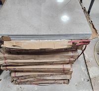 Stack of 8 boxes containing brand new ceramic tiles with light gray top tile visible and packaging labeled with dimensions and quantity.