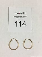 Photo showing front view of both gold hoop earrings next to auction lot number card