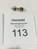 Side view of single gold stud earring with dark Fire Agate stone and sterling silver post backing visible.