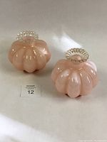Two coral pink Fenton melon perfume bottles with clear crimped tops, side by side on white background.