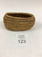 Front angled view of the small oval cedar root and beargrass basket showing the tight coiled weave and oval shape.