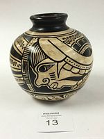 Front side view of the Chorotega pottery vase showing detailed depiction of a warrior face in traditional style, painted in black and beige.