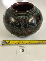 Front and size view showing the round pottery with a measuring tape for scale.
